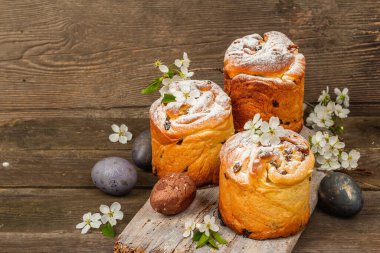 Paskalya pastası Cruffin 'i ya da boyalı yumurtalı tatlı ekmek kulich' i. Geleneksel şenlikli pişirme ve taze kiraz çiçekleri, şenlikli ahşap arka plan. Vintage panolar, rustik biçim, kopyalama alanı
