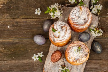 Paskalya pastası Cruffin 'i ya da boyalı yumurtalı tatlı ekmek kulich' i. Geleneksel şenlikli pişirme ve taze kiraz çiçekleri, şenlikli ahşap arka plan. Eski tahtalar, kırsal stil, üst görünüm