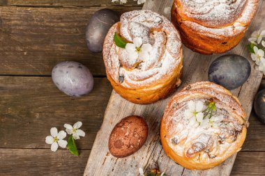 Paskalya pastası Cruffin 'i ya da boyalı yumurtalı tatlı ekmek kulich' i. Geleneksel şenlikli pişirme ve taze kiraz çiçekleri, şenlikli ahşap arka plan. Eski tahtalar, kırsal stil, üst görünüm