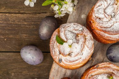 Paskalya pastası Cruffin 'i ya da boyalı yumurtalı tatlı ekmek kulich' i. Geleneksel şenlikli pişirme ve taze kiraz çiçekleri, şenlikli ahşap arka plan. Eski tahtalar, kırsal stil, üst görünüm