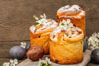 Paskalya pastası Cruffin 'i ya da boyalı yumurtalı tatlı ekmek kulich' i. Geleneksel şenlikli pişirme ve taze kiraz çiçekleri, şenlikli ahşap arka plan. Vintage panolar, rustik biçim, kopyalama alanı