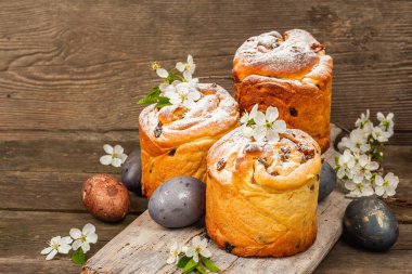Paskalya pastası Cruffin 'i ya da boyalı yumurtalı tatlı ekmek kulich' i. Geleneksel şenlikli pişirme ve taze kiraz çiçekleri, şenlikli ahşap arka plan. Vintage panolar, rustik biçim, kopyalama alanı