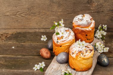Paskalya pastası Cruffin 'i ya da boyalı yumurtalı tatlı ekmek kulich' i. Geleneksel şenlikli pişirme ve taze kiraz çiçekleri, şenlikli ahşap arka plan. Vintage panolar, rustik biçim, kopyalama alanı
