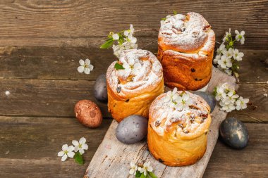 Paskalya pastası Cruffin 'i ya da boyalı yumurtalı tatlı ekmek kulich' i. Geleneksel şenlikli pişirme ve taze kiraz çiçekleri, şenlikli ahşap arka plan. Vintage panolar, rustik biçim, kopyalama alanı