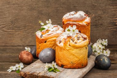 Paskalya pastası Cruffin 'i ya da boyalı yumurtalı tatlı ekmek kulich' i. Geleneksel şenlikli pişirme ve taze kiraz çiçekleri, şenlikli ahşap arka plan. Vintage panolar, rustik biçim, kopyalama alanı