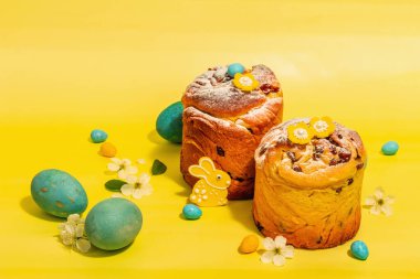 Paskalya keki Cruffin veya tatlı ekmek kulich ve geleneksel boyalı yumurta. Şenlikli pişirme ve kiraz çiçekleri. Modaya uygun sert ışık, koyu gölge, parlak sarı arkaplan, kopyalama alanı