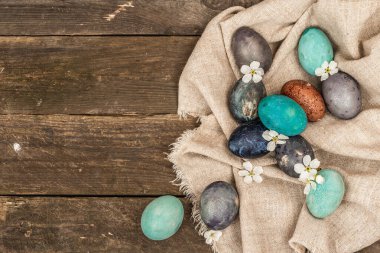 Paskalya yumurtaları ve kiraz çiçekleri eski ahşap arka planda. Kutlama kartı, geleneksel bahar sembolü. Modern sert ışık, karanlık gölge, düz uzanma, üst manzara
