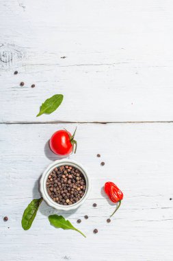 Modern culinary background with cherry tomatoes, spices and herbs. White wooden boards, trendy hard light, dark shadow, flat lay, top view