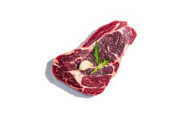Raw Ribeye steak with spices and herbs isolated on white background. A trendy hard light, dark shadow, flat lay, mockup, template, top view