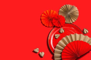 Happy Chinese New Year table setting concept. Oriental asian style paper fans on red background, minimal concept, flat lay, copy space