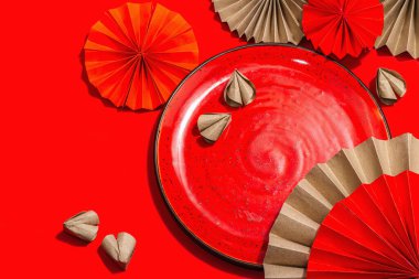 Happy Chinese New Year table setting concept. Oriental asian style paper fans on red background, minimal concept, flat lay, copy space
