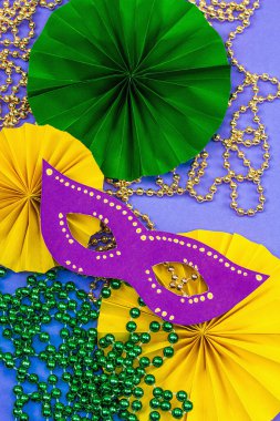 Festive Mardi Gras masquerade violet background. Fat Tuesday carnival, masks, beads, traditional decor. Symbolic colors, trendy hard light, dark shadow, flat lay, top view