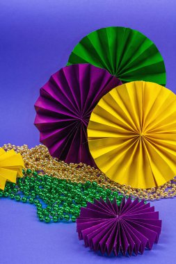 Festive Mardi Gras masquerade violet background. Fat Tuesday carnival, masks, beads, traditional decor. Symbolic colors, trendy hard light, dark shadow, flat lay, close up