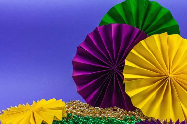 Festive Mardi Gras masquerade violet background. Fat Tuesday carnival, masks, beads, traditional decor. Symbolic colors, trendy hard light, dark shadow, flat lay, copy space