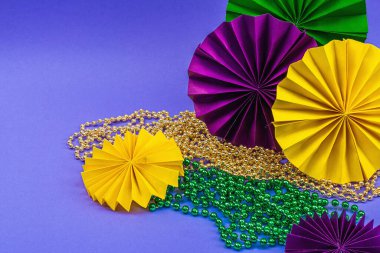 Festive Mardi Gras masquerade violet background. Fat Tuesday carnival, masks, beads, traditional decor. Symbolic colors, trendy hard light, dark shadow, flat lay, copy space