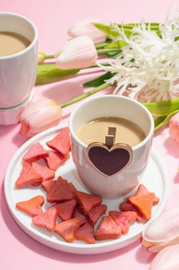 Valentine's Day romantic concept. Morning coffee, a bouquet of tulips, symbolic decor. Soft pink background, trendy hard light, dark shadow, close up