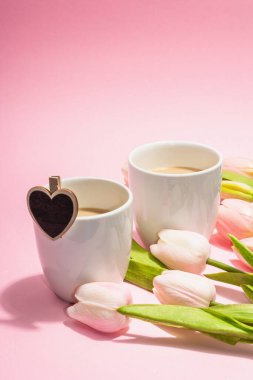 Valentine's Day romantic concept. Morning coffee, a bouquet of tulips, symbolic decor. Soft pink background, trendy hard light, dark shadow, copy space