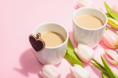Valentine's Day romantic concept. Morning coffee, a bouquet of tulips, symbolic decor. Soft pink background, trendy hard light, dark shadow, copy space