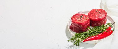 Raw Eye of round steak with spices and herbs on white background. Fresh meat for cooking healthy food. A trendy hard light, dark shadow, flat lay, banner format
