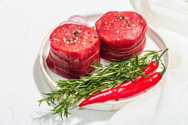 Raw Eye of round steak with spices and herbs on white background. Fresh meat for cooking healthy food. A trendy hard light, dark shadow, flat lay, copy space