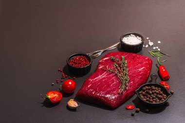 Flank steak with classic spices and herbs. Fresh raw meat cut, modern hard light, dark shadow, black stone concrete background, flat lay, copy space