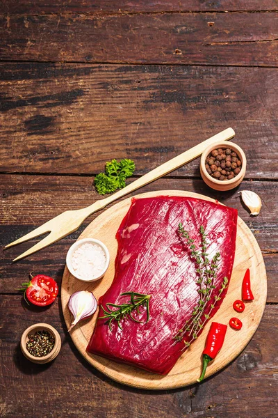 Close up of Flank steak with traditional spices and herbs. Fresh raw meat cut, old wooden background, flat lay, top view