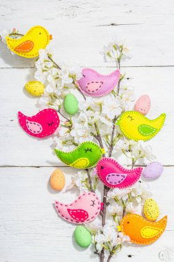Beautiful Easter background with traditional decor. Flowers, decorative eggs, birds and rabbits. Modern hard light, dark shadow, white boards, flat lay, top view