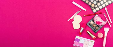 Make up set with colorful eyeshadow palettes, brushes, sponges and flowers. Trendy viva magenta color background, spring festive cosmetic concept, flat lay, banner format