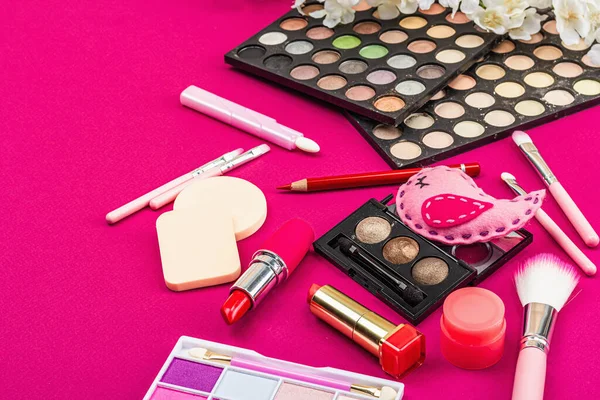 Make up set with colorful eyeshadow palettes, brushes, sponges and flowers. Trendy viva magenta color background, spring festive cosmetic concept, flat lay, copy space