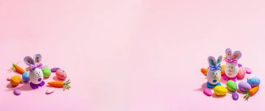 Festive Easter composition. Traditional symbols and decor - rabbits, eggs, carrots. Pastel design, trendy hard light, dark shadow, pink background, banner format