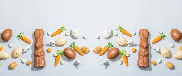 Easter background with eggs, rabbits and carrots. Festive spring composition with traditional symbols, modern hard light, dark shadow, flat lay, banner format