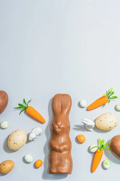 Easter background with eggs, rabbits and carrots. Festive spring composition with traditional symbols, modern hard light, dark shadow, flat lay, top view