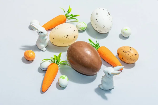 Easter background with eggs, rabbits and carrots. Festive spring composition with traditional symbols, modern hard light, dark shadow, flat lay, close up
