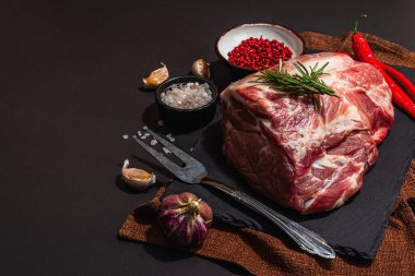 Baharatlı ve otlu çiğ domuz filetosu. Taze et, protein yemeği pişirmek için malzeme, sağlıklı gıda yaşam tarzı. Modaya uygun sert ışık, karanlık gölge, siyah taş beton zemin, kopyalama alanı