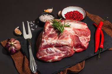 Baharatlı ve otlu çiğ domuz filetosu. Taze et, protein yemeği pişirmek için malzeme, sağlıklı gıda yaşam tarzı. Modaya uygun sert ışık, karanlık gölge, siyah taş beton arka plan, kapat