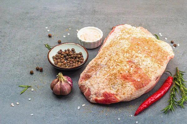 Raw pork shoulder with spices and herbs. Fresh meat cut, ingredient for cooking protein food, healthy food lifestyle. Grey stone concrete background, copy space