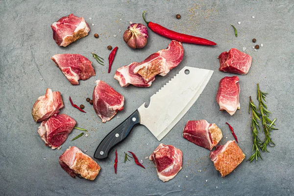 Raw pork shoulder pieces with ground spices. Fresh meat cut, ingredient for cooking protein food, healthy food lifestyle. Grey stone concrete background, top view