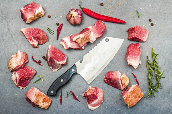 Raw pork shoulder pieces with ground spices. Fresh meat cut, ingredient for cooking protein food, healthy food lifestyle. Grey stone concrete background, top view