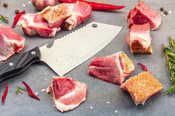 Raw pork shoulder pieces with ground spices. Fresh meat cut, ingredient for cooking protein food, healthy food lifestyle. Grey stone concrete background, close up