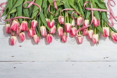 Beyaz ahşap arka planda taze pembe laleler. Anneler Günü ya da Sevgililer Günü için şölen konsepti. Tebrik kartı, Paskalya düzlüğü, sert ışık, koyu gölge, üst manzara.