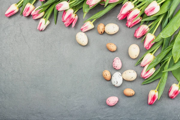 stock image Easter flat lay with colorful eggs and tulips. Traditional decor, festive greeting card, holiday concept, gray stone concrete background, top view