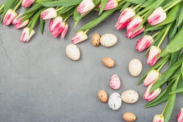 Stock image Easter flat lay with colorful eggs and tulips. Traditional decor, festive greeting card, holiday concept, gray stone concrete background, top view