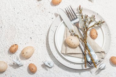 Yumurtalı, tavşanlı ve söğütlü Paskalya sofrası. Geleneksel bayram sembolleri, tebrik kartları, düz yatış. Modaya uygun sert ışık, koyu gölge, alçı arka plan, üst görünüm