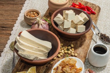 Tofu hazırlamak için gerekli malzemeler. Taze doğranmış peynir, baharatlar, otlar ve soya sosu. Modaya uygun sert ışık, karanlık gölge, eski ahşap arka plan, kapat