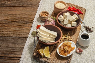 Tofu hazırlamak için gerekli malzemeler. Taze doğranmış peynir, baharatlar, otlar ve soya sosu. Modaya uygun sert ışık, koyu gölge, eski ahşap zemin, kopyalama alanı