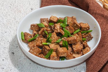 Kızarmış teriyaki tofu, soğanlı ve susamlı. Protein ve kalsiyum açısından zengin sağlıklı vejetaryen eti. Modaya uygun sert ışık, koyu gölge, alçı arka plan, kapat