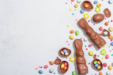 Geleneksel Paskalya tatlıları, yumurtalı, çikolatalı tavşan, yenilebilir şenlikli dekorasyon. Çocuk arayışı, modaya uygun sert ışık, karanlık gölge. Hafif taş zemin, düz zemin, üst manzara