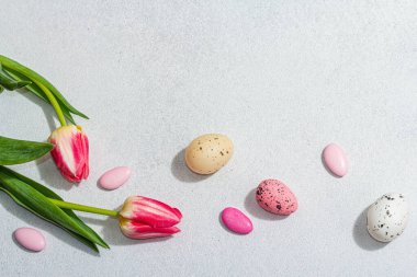 Paskalya yumurtalı pembe laleler. Kutlama konsepti, tebrik kartı, düz konum, sert ışık, koyu gölge, üst görünüm