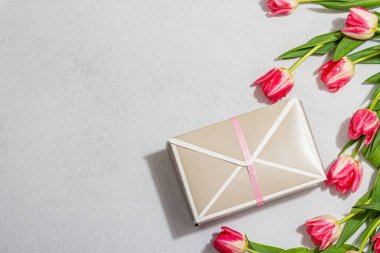 Sıfır israf bahar hediyesi konsepti. Pembe laleler, yıldönümü için sürpriz karton kutu, Anneler Günü veya Sevgililer Günü. Mutlu yıllar tebrik kartı, aydınlık taş arka plan, üst manzara