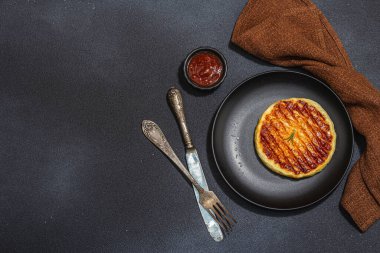 Tabakta ızgara Halloumi peyniri. Çatal bıçak takımı, piknik ya da barbekü için geleneksel yemek. Modaya uygun sert ışık, koyu gölge, düz zemin, siyah taş beton zemin, üst manzara